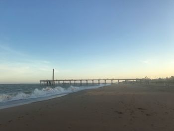 Scenic view of beach against clear sky during sunset