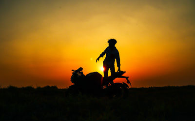 Side view of man riding horse against orange sky during sunset