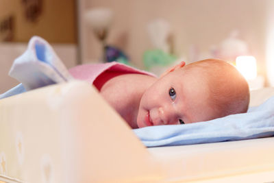 Portrait of cute baby boy lying on bed at home