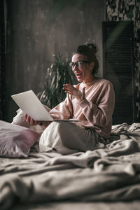 Midsection of woman using mobile phone while sitting on bed