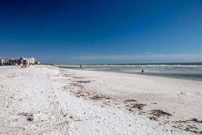 Scenic view of beach against clear blue sky