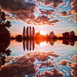 Silhouette trees by lake against sky during sunset