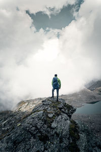 Rear view of man standing on rock against mountain