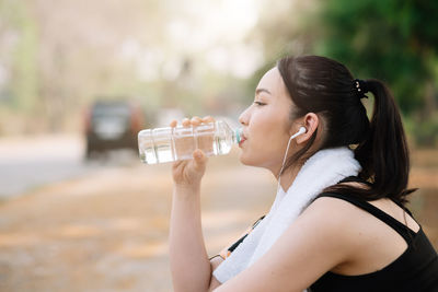 Midsection of woman drinking glass with water