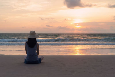 Woman looking at sea against sky during sunset