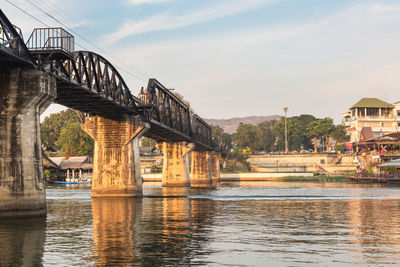 Bridge over river in city against sky