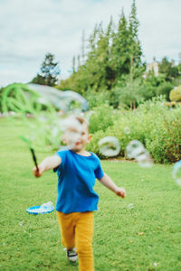 Young boy running in park playing with bubbles