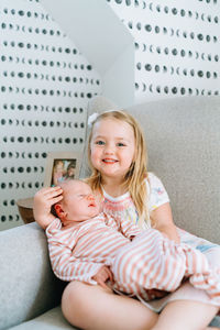 Straight on portrait of a young girl holding her baby sister