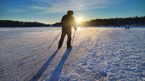 Silhouette man skiing on snow field against sky during sunset