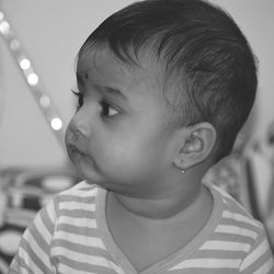 Close-up of cute baby girl looking away at home