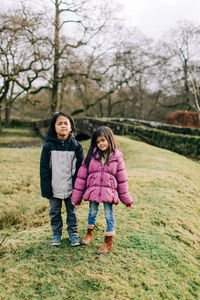 Full length portrait of happy girl standing against trees