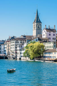 Sailboats in canal by buildings against sky