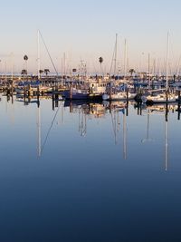 Sailboats moored in harbor against clear blue sky