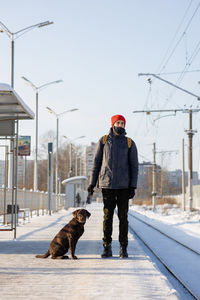 Man with dog standing on snow during winter