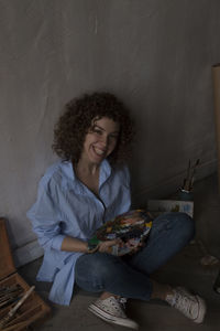 Young woman sitting on wall at home