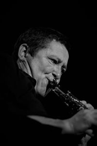 Portrait of man holding camera over black background