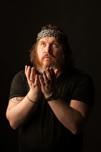 Portrait of young man wearing hat against black background