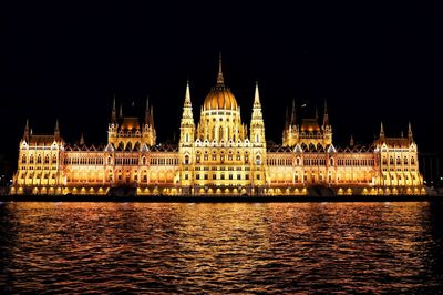 Illuminated hungarian parliament building by river at night