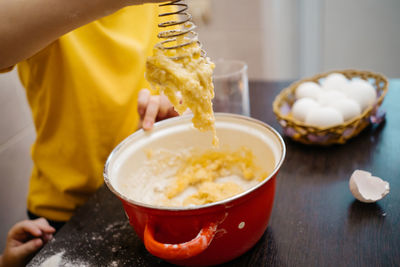 Child kneads dough for holiday cake, white eggs on the table