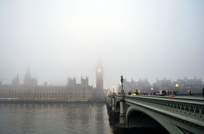 Bridge over river in city against sky