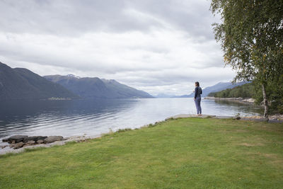 A man drinking a cup of coffee looking across a fjord in norway