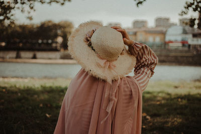 Rear view of woman wearing hat standing on land