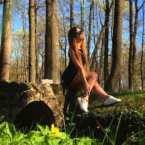 Full length of young woman on tree trunk in forest