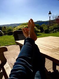 Low section of woman with legs on table against sky