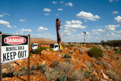 Road sign on rock against sky