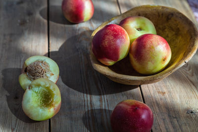 Red and green mini nectarine in a wooden bowl.