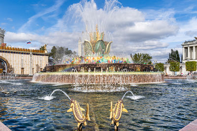 Fountain in city against sky