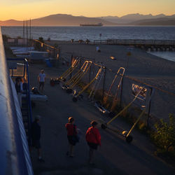 Tourists on shore at sunset