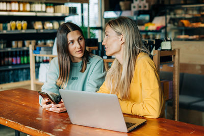 Two businesswomen colleagues are discussing a project while sitting in a cafe.