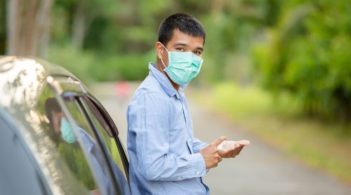 Portrait of young man standing by car