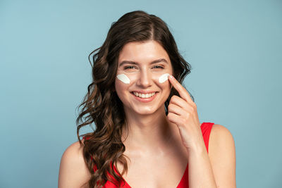 Portrait of a smiling young woman against blue background