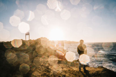 Person standing at beach against sky