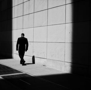 Rear view of man walking on tiled floor