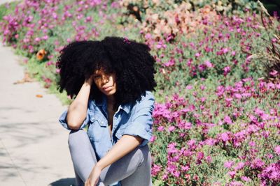 Portrait of woman with frizzy hair sitting in garden