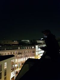 Side view of illuminated cityscape against sky at night