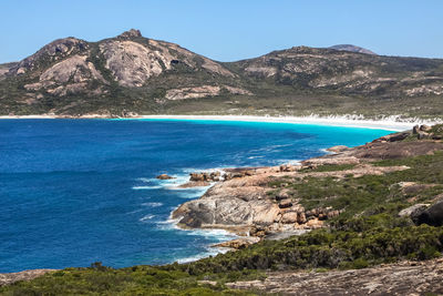 Scenic view of sea and mountains against clear blue sky