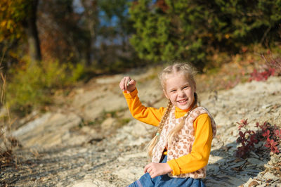Little girl playing . preschooler child sits on the ground on a clear sunny autumn day in the forest