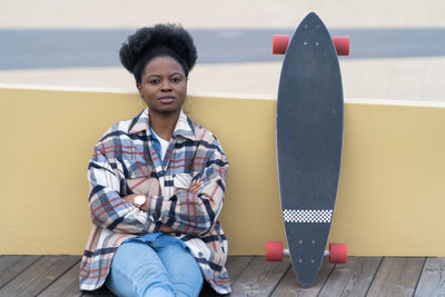 Young african woman relax after skateboarding on city street sit calm pondering. urban lifestyle