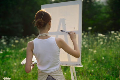 Rear view of woman standing against plants