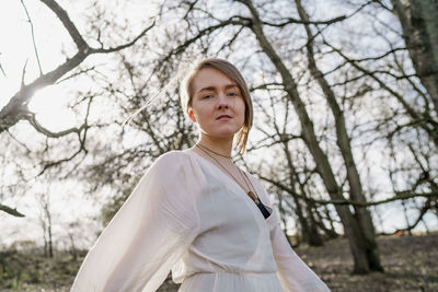 Portrait of woman standing by tree