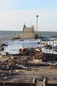 Abandoned pier on beach against sky