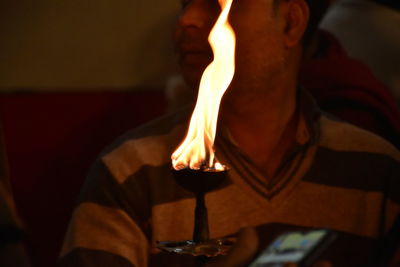 Close-up of man holding lit candles