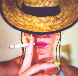 Close-up portrait of woman holding hat