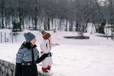 Rear view of woman standing on snow covered field