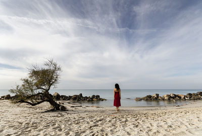 Rear view of woman on beach against sky