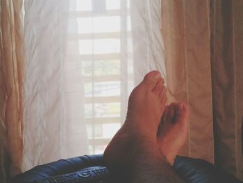 Low section of woman relaxing on bed